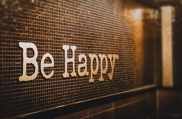 značka, nápis „be happy“ na stěně